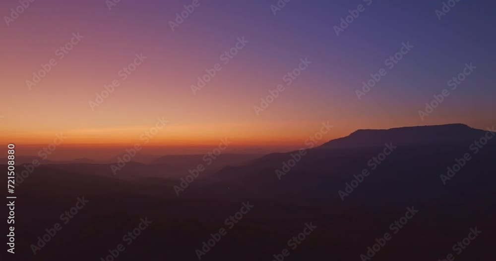 Aerial view A breathtaking sunset paints the sky with vibrant hues of orange and red, .casting a warm glow over the majestic mountains in a tranquil evening landscape.colorful layer of mountain range. Aerial view A breathtaking sunset paints the sky with vibrant hues of orange and red, .casting a warm glow over the majestic mountains in a tranquil evening landscape.colorful layer of mountain range.