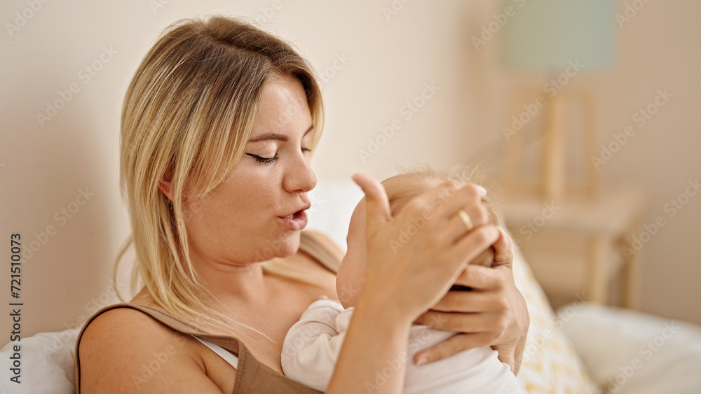 Mother and daughter lying on bed hugging at bedroom