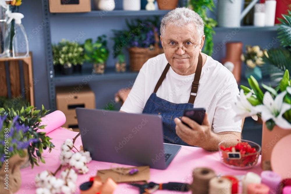 Middle age grey-haired man florist using smartphone and laptop at florist Middle age grey-haired man florist using smartphone and laptop at florist