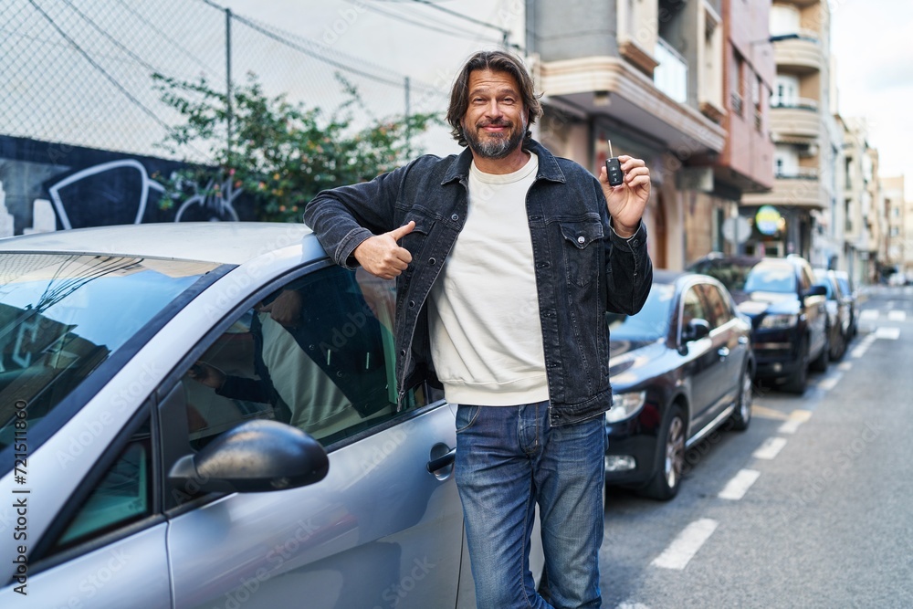 Middle age man smiling confident holding key of new car at street