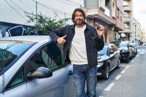 Middle age man smiling confident holding key of new car at street © Krakenimages.com