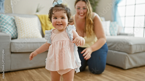 Warm mother-daughter duo smiling and exuding confidence in their lovely home, joyfully huddled on the living room sofa - a delightful expression of casual, positive family lifestyle indoors. © Krakenimages.com
