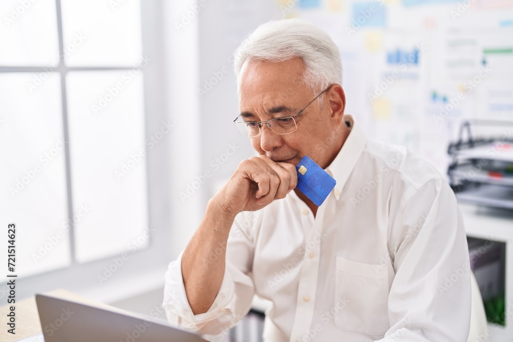 Middle age grey-haired man business worker using laptop and credit card at street