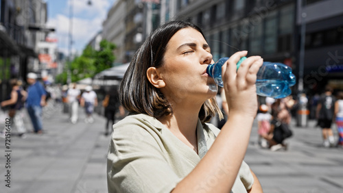 Young beautiful hispanic woman standing drinking water in the streets of Vienna