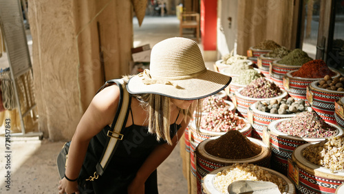 Quadro su tela A young woman explores a traditional market in dubai, examining spices and herbs in an arabic souq