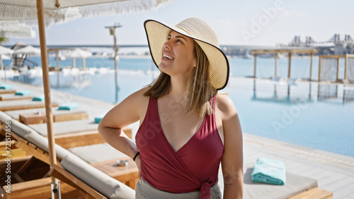 Photo A smiling woman in a sunhat enjoys a luxurious poolside ambiance at a tropical resort overlooking the sea