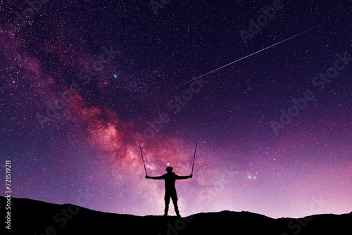 Silhouette of a hiker standing on the hill, on the milky way galaxy background. © Inga Av