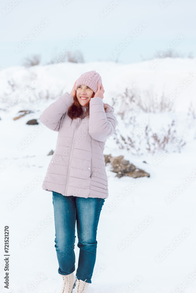 Beautiful and happy woman in winter clothes in the cold holds her hat and smiles Beautiful and happy woman in winter clothes in the cold holds her hat and smiles