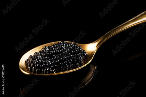 Extreme close up of a golden spoon with black caviar. Beautiful light and glare on fish eggs. Created using generative AI.