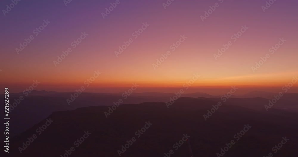 Aerial view A breathtaking sunset paints the sky with vibrant hues of orange and red, .casting a warm glow over the majestic mountains in a tranquil evening landscape.colorful layer of mountain range. Aerial view A breathtaking sunset paints the sky with vibrant hues of orange and red, .casting a warm glow over the majestic mountains in a tranquil evening landscape.colorful layer of mountain range.