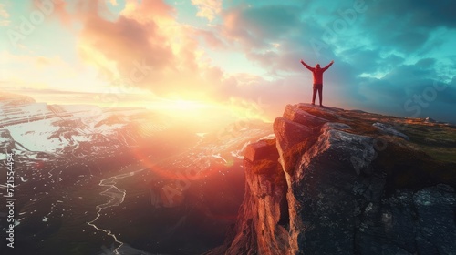On the edge of a rocky cliff a man raises his hands to heaven as a sign of freedom or victory and in the background a fantastic landscape.