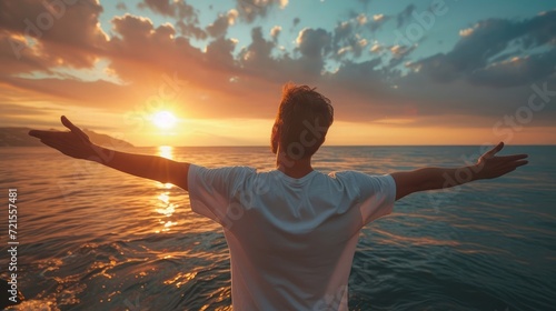Young man arms outstretched by the sea at sunrise enjoying freedom and life, people travel wellbeing concept © buraratn