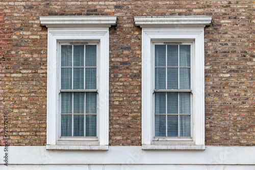 two classic white windows of typical london architecture with red brick wall