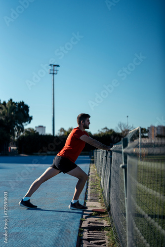 Chico joven estirando y realizando deporte al aire libre un día soleado