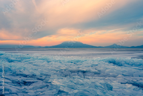 Fonyod, Hungary - Beautiful icebergs on the shore of the frozen Balaton. Badacsony and Gulacs with a spectacular cloudy sunset in the background. Winter landscape. photo