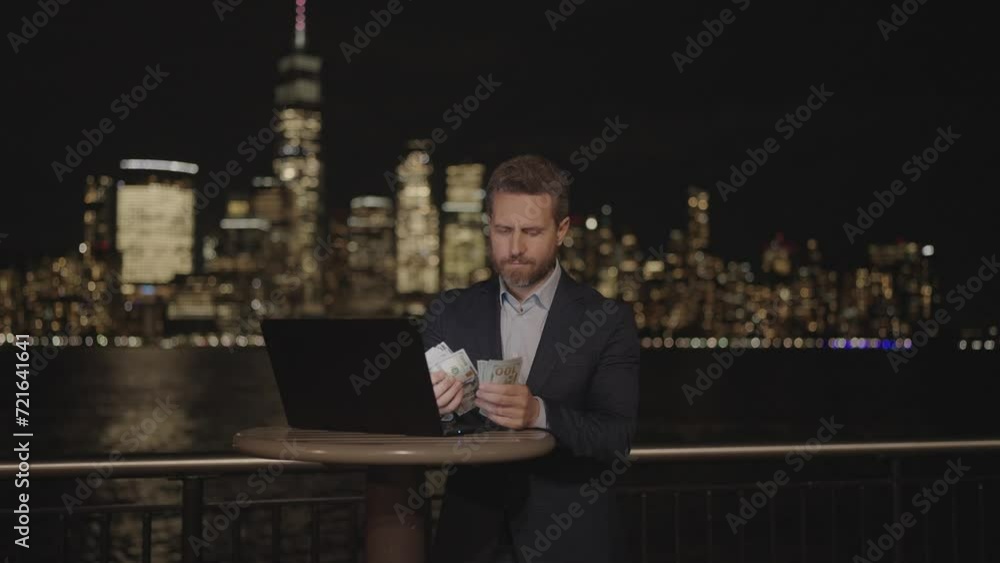 Businessman counting money in night city. Business man counting US banknotes at the night city. Successful businessman counts, show cash money on office building in NYC. Money in night Manhattan. Businessman counting money in night city. Business man counting US banknotes at the night city. Successful businessman counts, show cash money on office building in NYC. Money in night Manhattan.