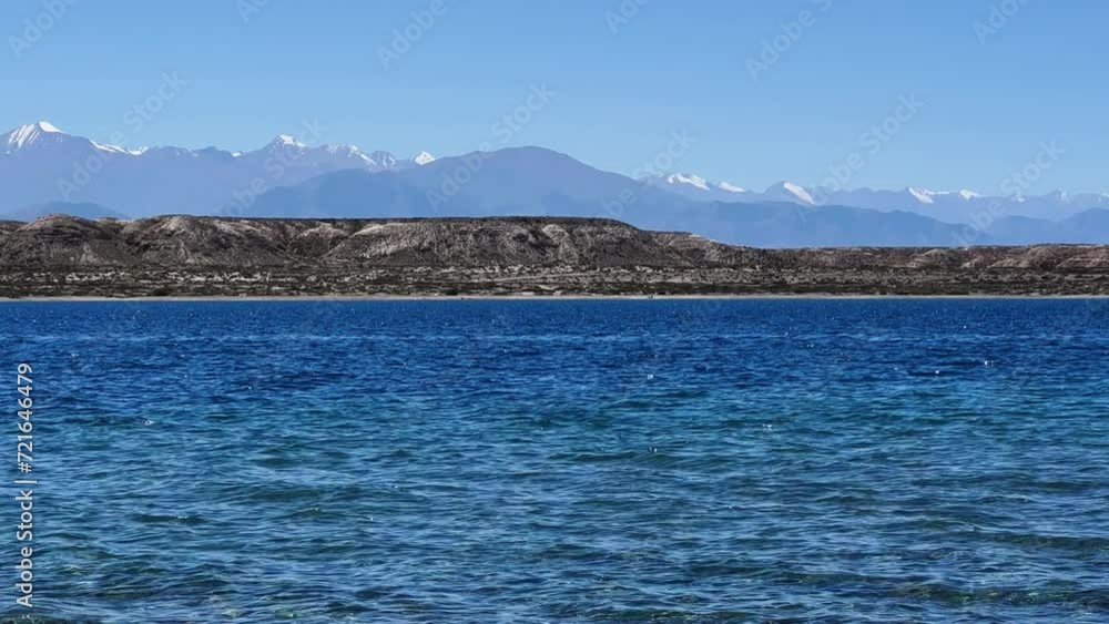 View of Issyk-Kul mountain lake, Kyrgyzstan. Waves splash on a sandy beach with rocks. Calm, peaceful natural background. Lake with a view of the Tien Shan Mountains. Kyrgyzstan 4K View of Issyk-Kul mountain lake, Kyrgyzstan. Waves splash on a sandy beach with rocks. Calm, peaceful natural background. Lake with a view of the Tien Shan Mountains. Kyrgyzstan 4K