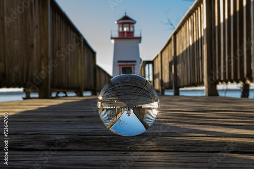 Reflection with double sunburst of Lighthouse Landing Lighthouse on boardwalk through lensball in Grand Rivers, KY