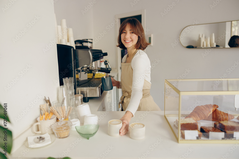 Portrait of a happy female barista standing behind the counter in a coffee shop Portrait of a happy female barista standing behind the counter in a coffee shop