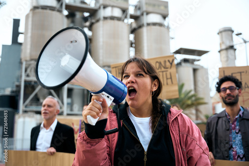 Angry and rebellious woman speaking and protesting with megaphone at demonstration at climate change and global warming. Group of activists people at a pro-earth manifestation with banners © CarlosBarquero