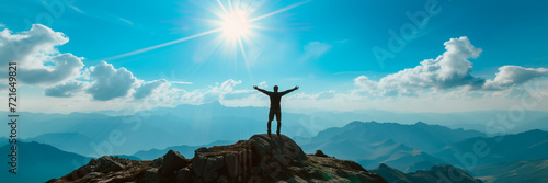 Panorama of young successful man hiker silhouette open arms on mountain peak