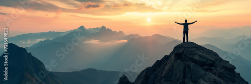 Panorama of young successful man hiker silhouette open arms on mountain peak photo