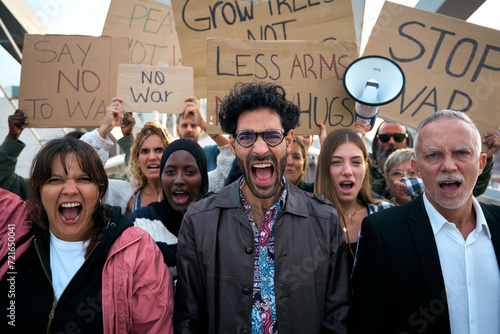 Multiracial and diverse ages people protesting against war and violence in the world looking at camera. Group of activists with anti-war banners at a demonstration for peace and human rights. 