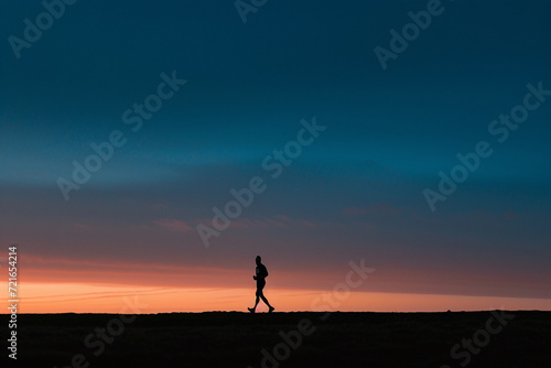 The solitary figure of a runner, silhouetted against the dawn sky, exemplifies endurance and commitment in a minimalist yet impactful image