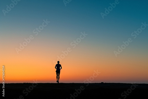 The solitary figure of a runner, silhouetted against the dawn sky, exemplifies endurance and commitment in a minimalist yet impactful image