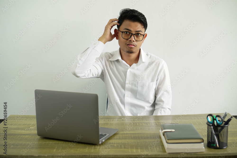 young asian businessman in a workplace with an expression of frustration and not understanding, wearing white shirt with glasses isolated young asian businessman in a workplace with an expression of frustration and not understanding, wearing white shirt with glasses isolated
