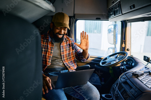 Happy black truck driver making video call from vehicle cabin.