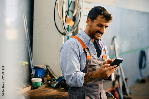 Happy mechanic using smart phone while working in repair shop. photo