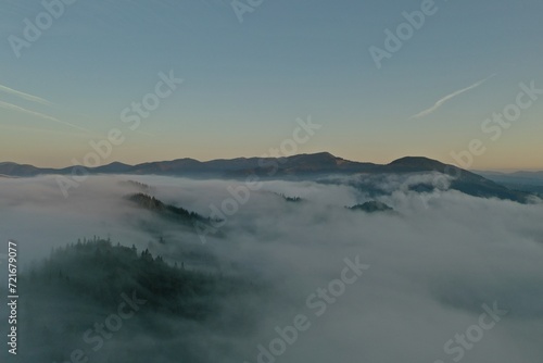 Aerial view of beautiful mountains covered with fluffy clouds in morning