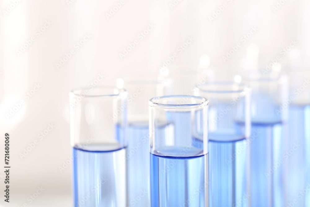 Laboratory analysis. Many glass test tubes with light blue liquid on blurred background, closeup Laboratory analysis. Many glass test tubes with light blue liquid on blurred background, closeup