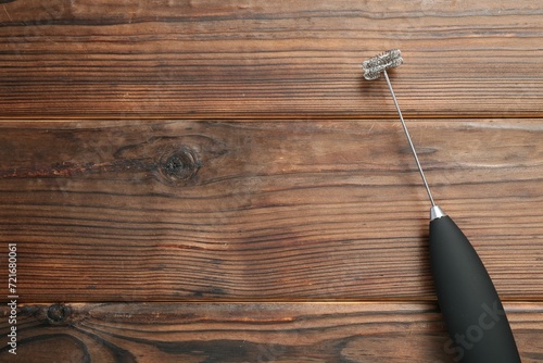 Black milk frother wand on wooden table, top view. Space for text