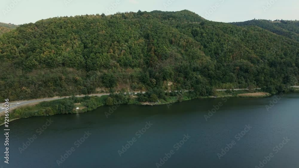 Drone ascends and captures a large wooded hills and a river with bridge over it Drone ascends and captures a large wooded hills and a river with bridge over it
