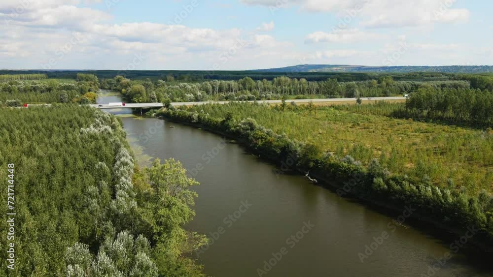 A bridge with cars and trucks over narrow lake and woods surrounding it A bridge with cars and trucks over narrow lake and woods surrounding it