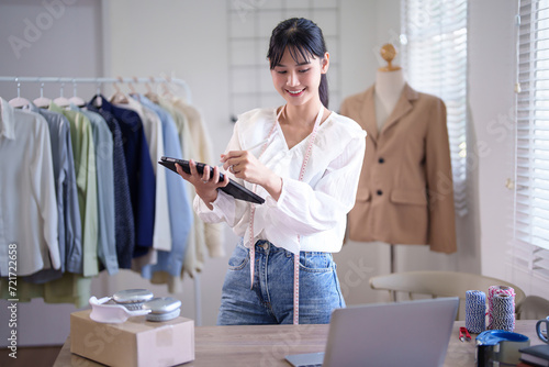 Fototapeta Young asian merchant women wearing measure tape in her neck and writing client i