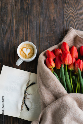 Fresh orange tulips with open book or diary on wooden background. Springtime #721729698
