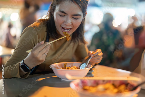 Traveler Asian woman enjoy eating noodle at night market. traditional Chiang Mai Thailand street food.