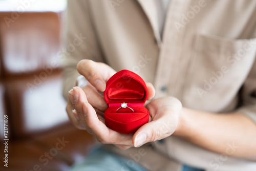 Wedding proposal surprise gift with luxury diamond ring in red heart jewellery box while groom hand holding and open it. Prepare for bridal engagement culture in Valentine day