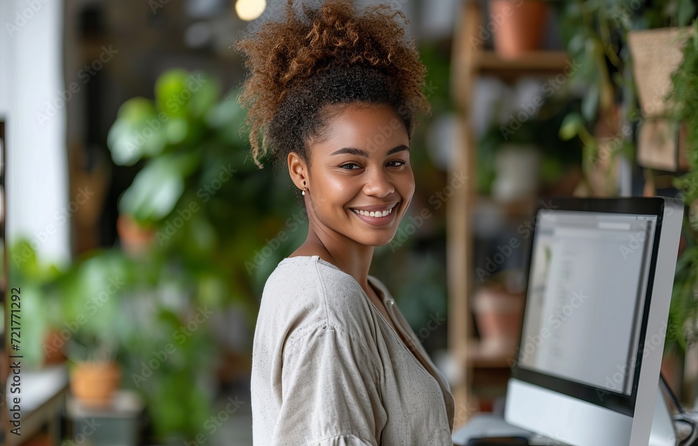 Responding on business e-mail. Beautiful young African woman working using computer and smiling while standing in workshop Responding on business e-mail. Beautiful young African woman working using computer and smiling while standing in workshop