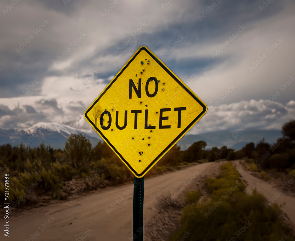 A road sign stating No Outlet riddled with bullet holes