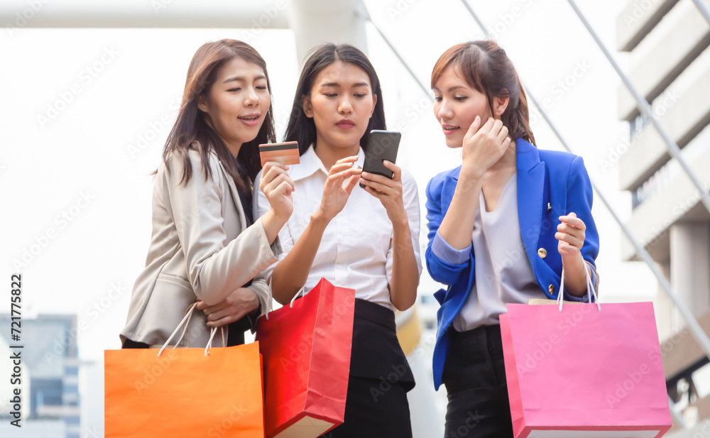 Group of young women carrying shopping bags while walking along the street. Happy Life and Shopping Concepts Group of young women carrying shopping bags while walking along the street. Happy Life and Shopping Concepts