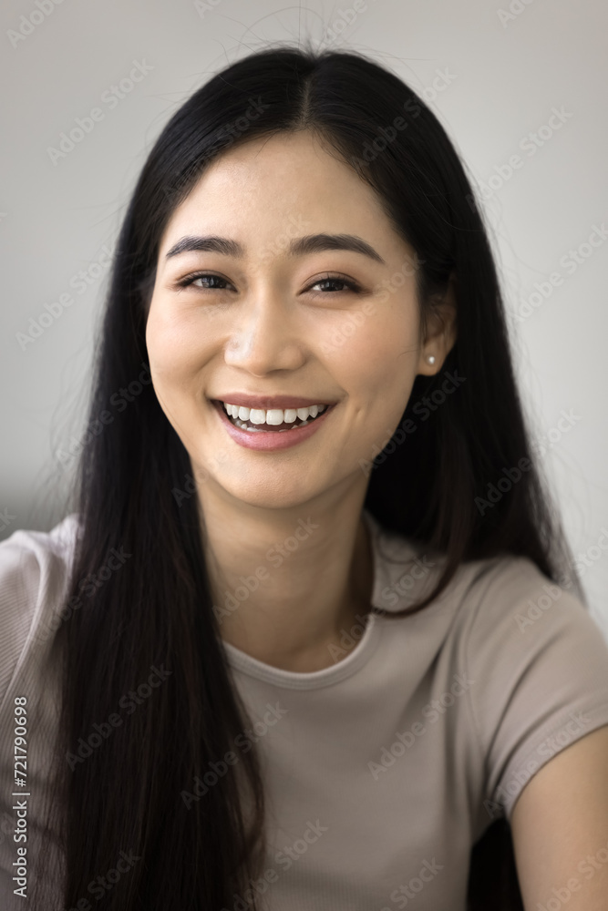 Cheerful young Asian woman head shot vertical portrait. Happy beautiful Chinese 20s girl with black straight long hair looking at camera with toothy smile, posing for vertical selfie portrait Cheerful young Asian woman head shot vertical portrait. Happy beautiful Chinese 20s girl with black straight long hair looking at camera with toothy smile, posing for vertical selfie portrait