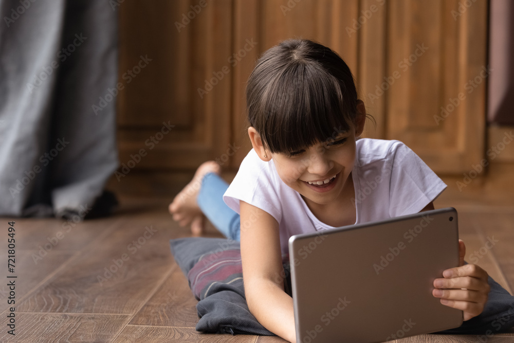 Gen z everyday. Smiling little hispanic kid girl lying on soft pillow on floor with heating learn online using digital pad. Happy preteen child watch web school video play game on tablet. Copy space Gen z everyday. Smiling little hispanic kid girl lying on soft pillow on floor with heating learn online using digital pad. Happy preteen child watch web school video play game on tablet. Copy space