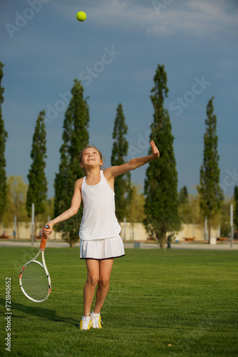 Girl tennis school age in a suit with a racket and a ball shows the elements of the sport. © Fotoproff