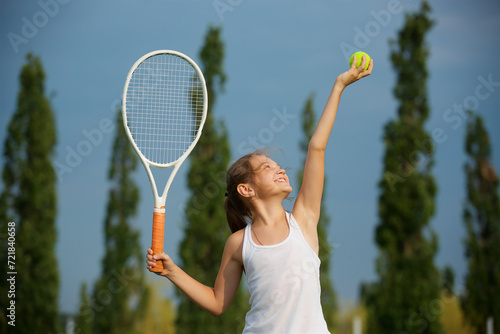 Girl tennis school age in a suit with a racket and a ball shows the elements of the sport. © Fotoproff