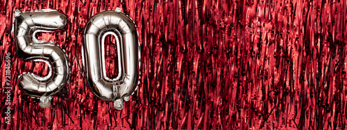 Silver foil balloon number 50 on a background of red tinsel decoration. Birthday greeting card, inscription fifty. Anniversary event. Banner. photo