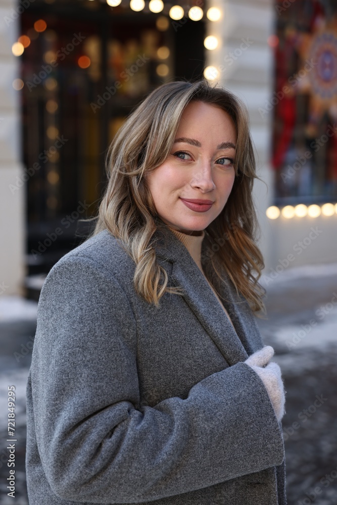 Fototapeta premium Portrait of charming woman on city street in winter